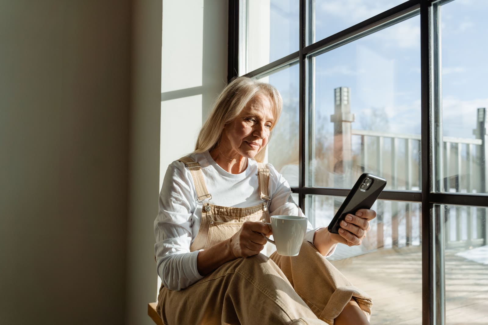 A woman with a coffee, relaxed in a sunny window